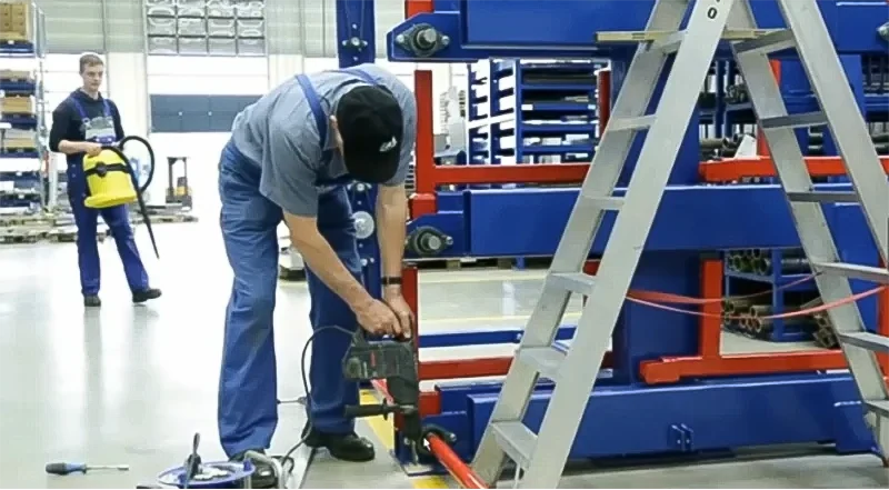 Worker anchoring the heavy-duty base of a telescopic cantilever rack to the floor