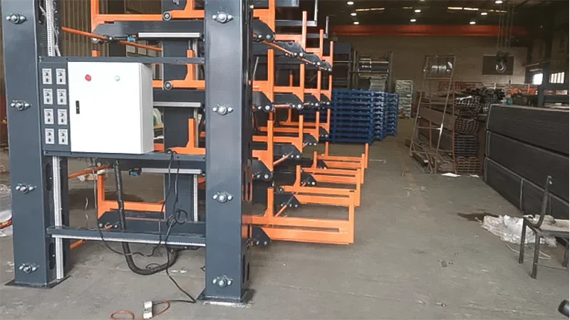 Overhead crane accessing heavy metal profiles on a red rolling cantilever rack system.