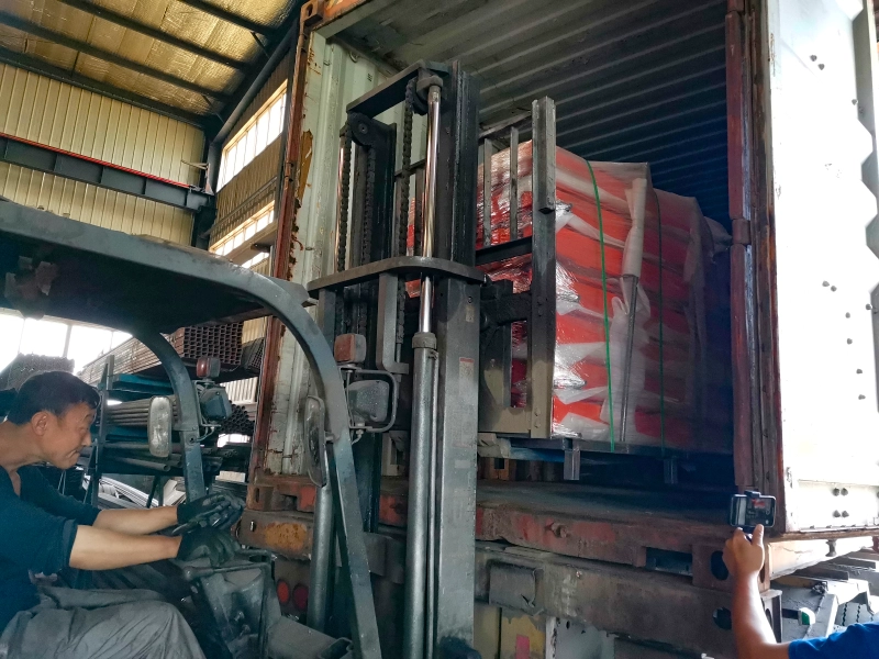 Forklift loading a steel telescopic cantilever rack with wrapped long materials into a shipping container