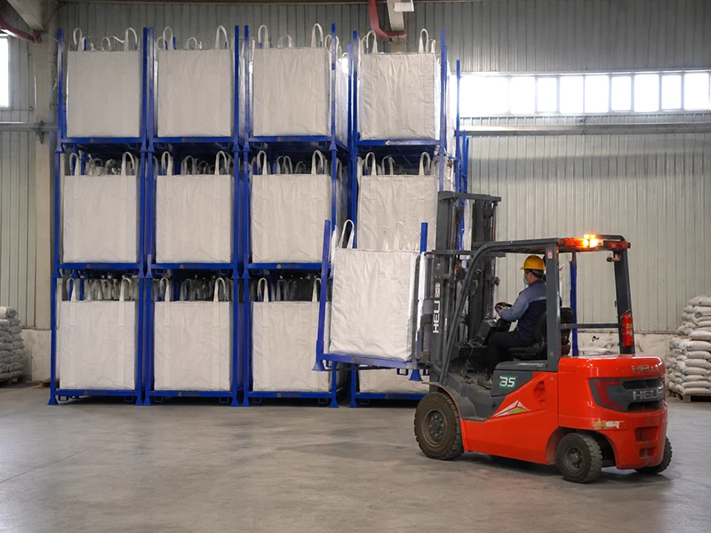 Forklift stacking modular steel post pallets with FIBC bulk bags in agricultural feed warehouse.