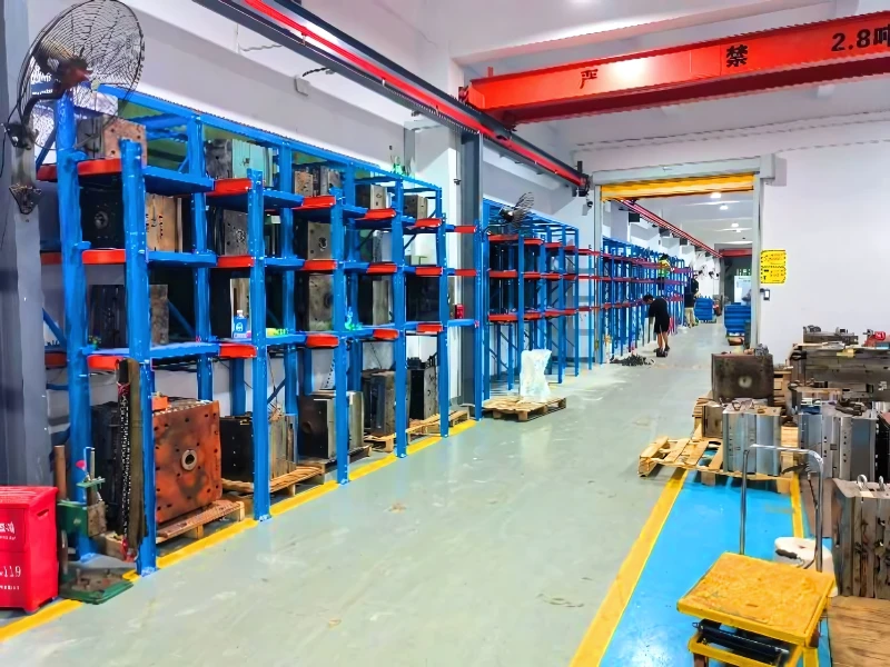 Blue roll-out mold racks in a hardened factory aisle with overhead crane track