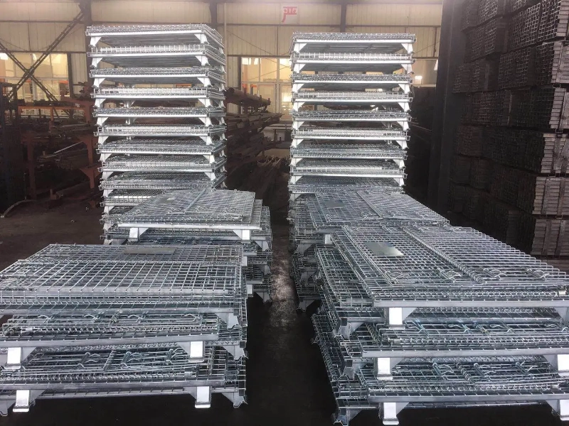 Columns of flat-collapsed steel wire mesh containers stacked in warehouse for optimal space utilization.