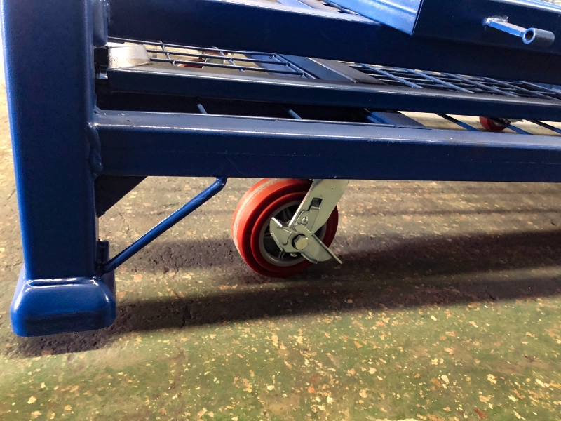 Close-up van rood polyurethaan zwenkwiel met rem op blauwe stalen container