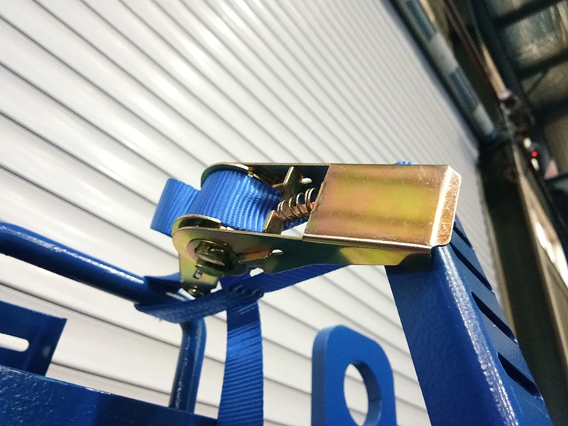 Close-up of galvanized ratchet buckle and blue webbing on powder-coated A-frame rack for glass transport