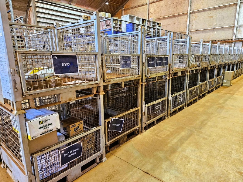 Two-level stacked wire pallet cages in warehouse with label tags