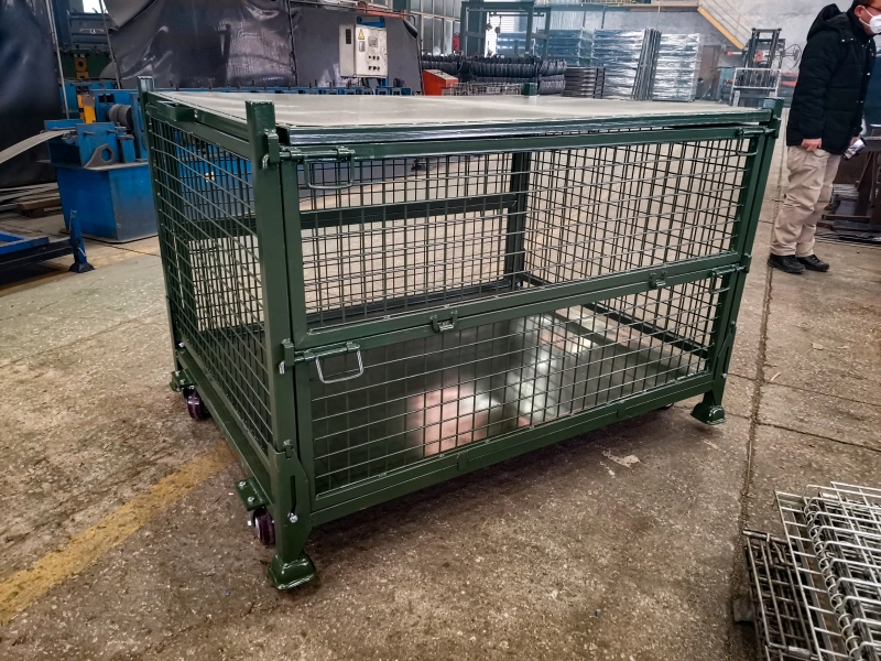Finished green lidded steel wire container with casters in factory workshop
