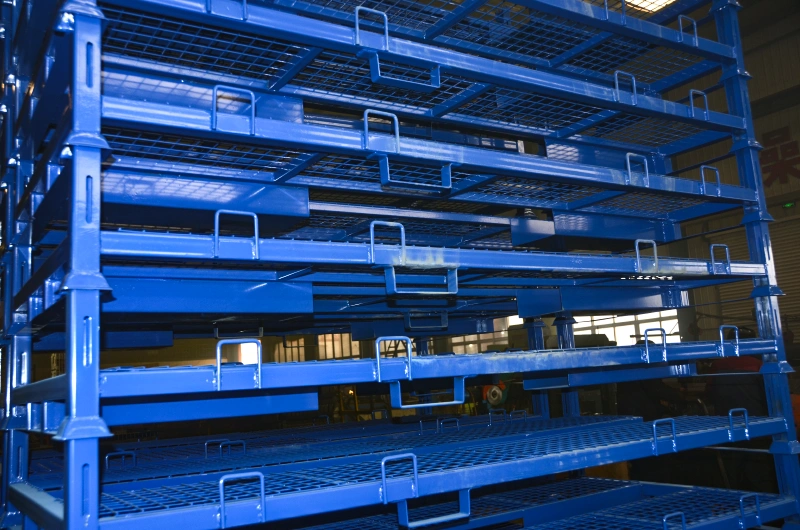 Stapelbare blauwe stalen motorpalletstellingen met gaasdekken gestapeld in magazijnverzendbaan