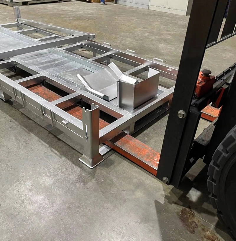 Close-up of forklift forks entering steel motorcycle shipping pallet base with galvanized wheel chock