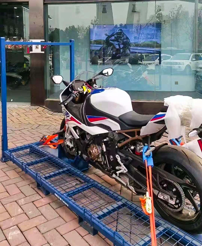 BMW sport motorcycle secured on blue steel shipping pallet with wheel chock and tie-down straps