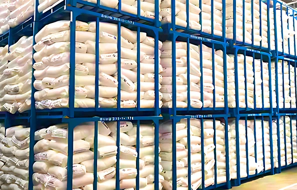 Stacked blue steel racks with side protective grills holding white woven bags in a high density warehouse
