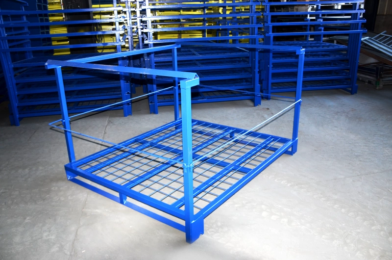 Empty blue steel nestainer rack with wire mesh deck and side safety bars on concrete workshop floor