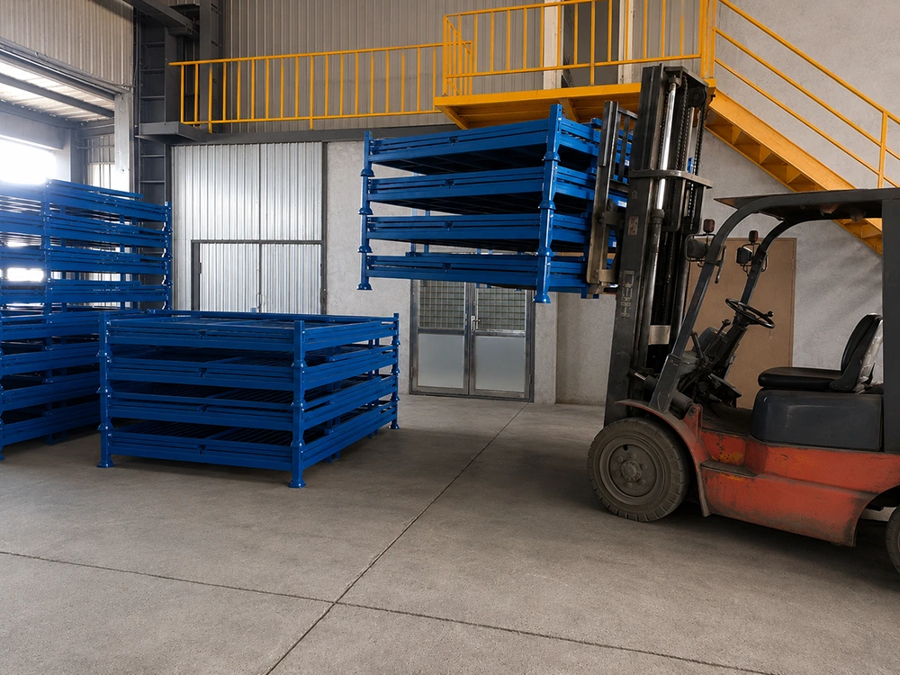Forklift handling blue stackable steel stillage racks with corner posts in an industrial warehouse