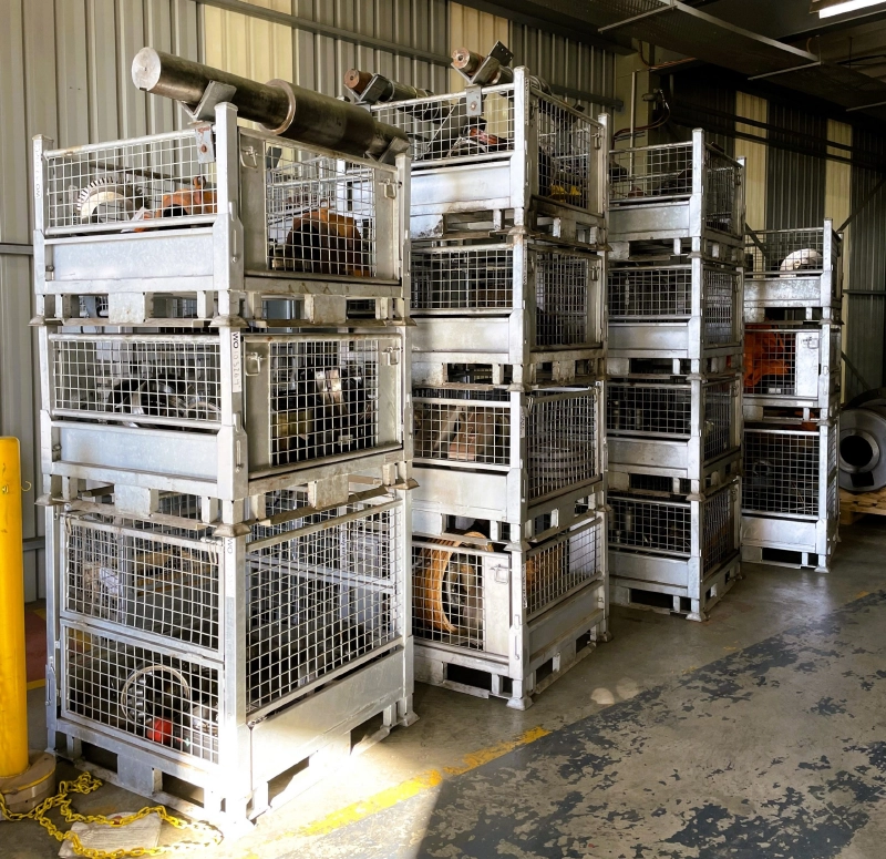 Multi-layer stacked galvanized steel cages loaded with heavy industrial shafts and gears
