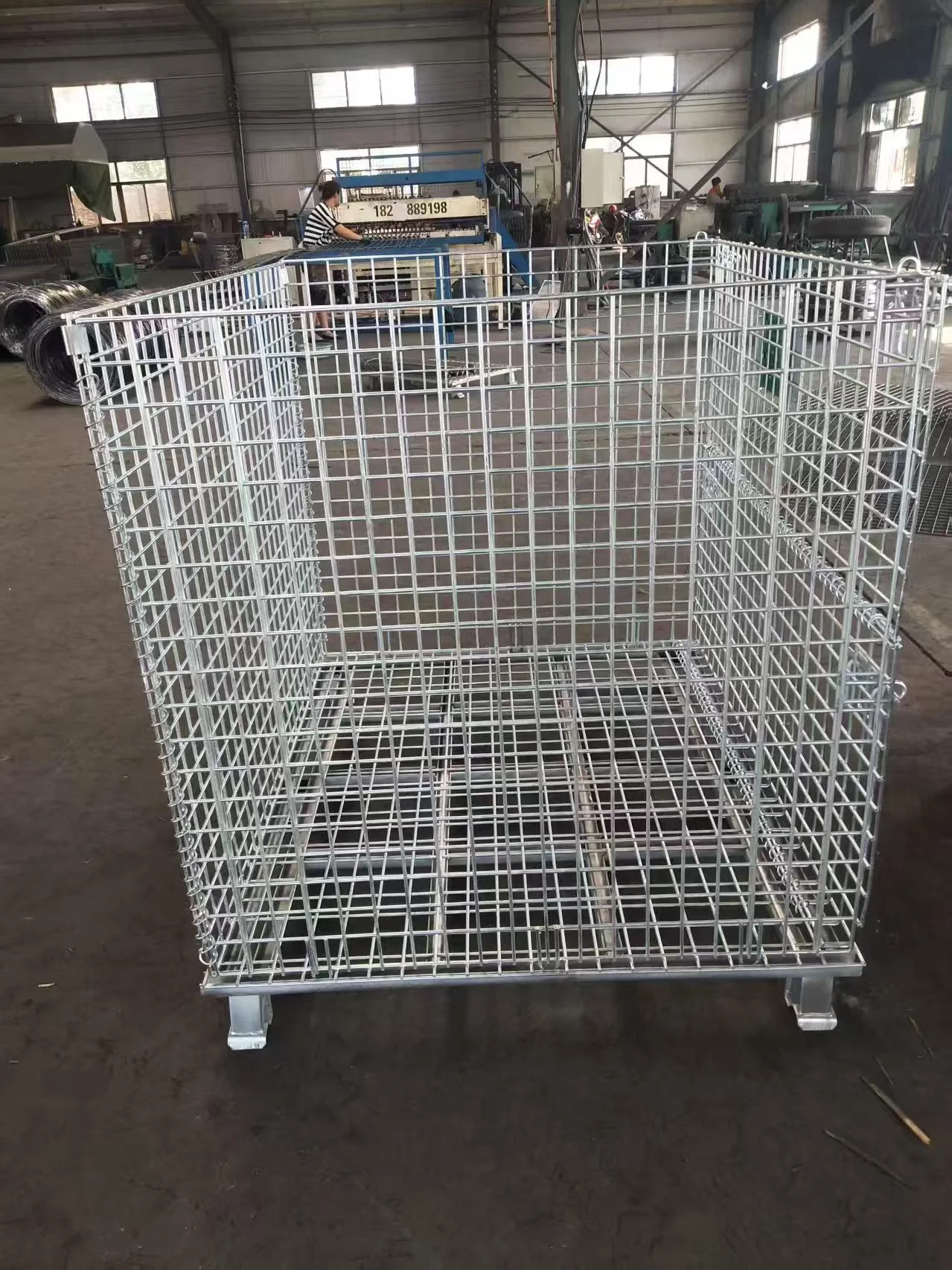 Extra tall wire mesh warehouse cage assembled in manufacturing shop near automatic grid welder.